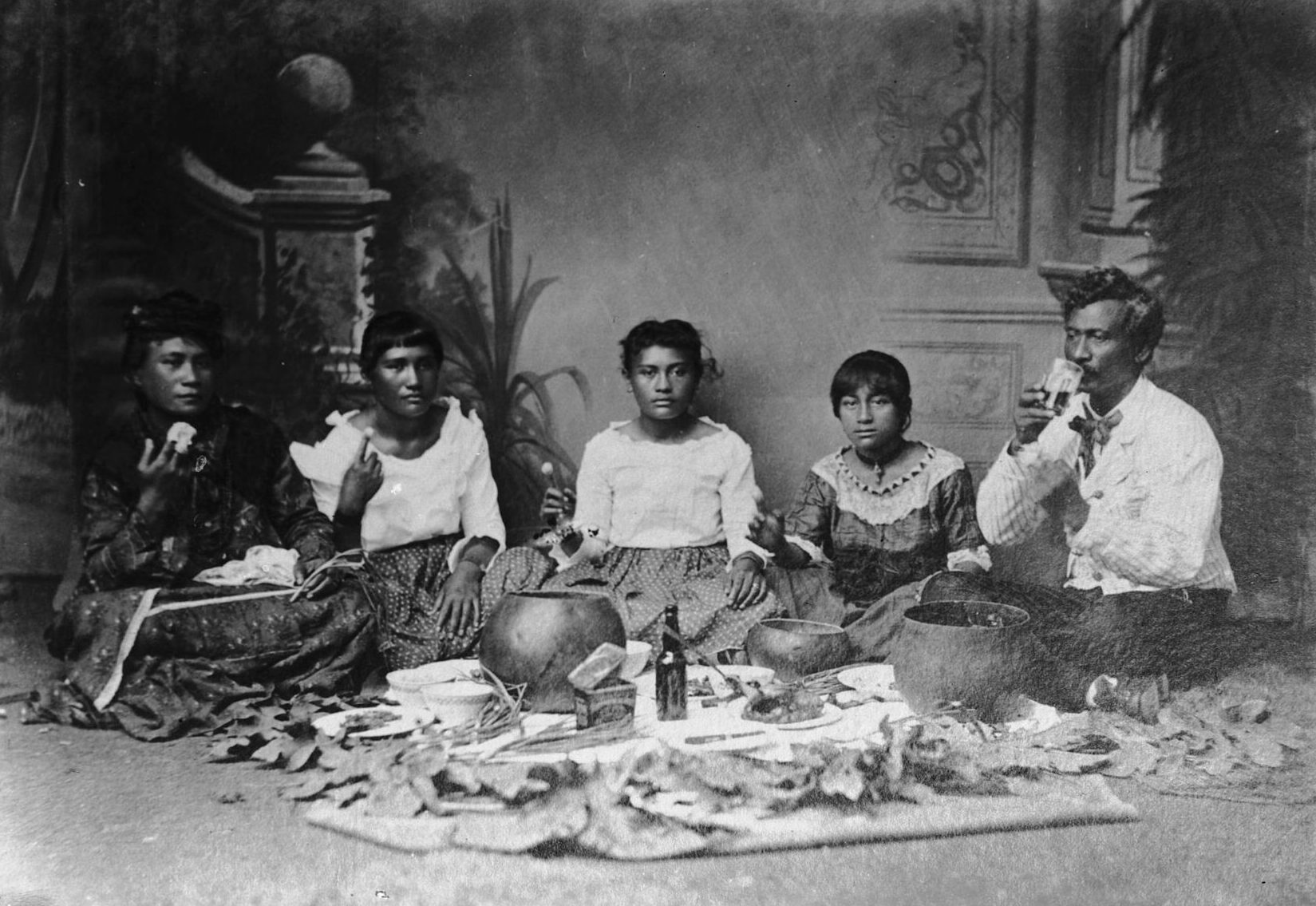Historic photograph of a Native Hawaiian family seated together sharing poi, 1907