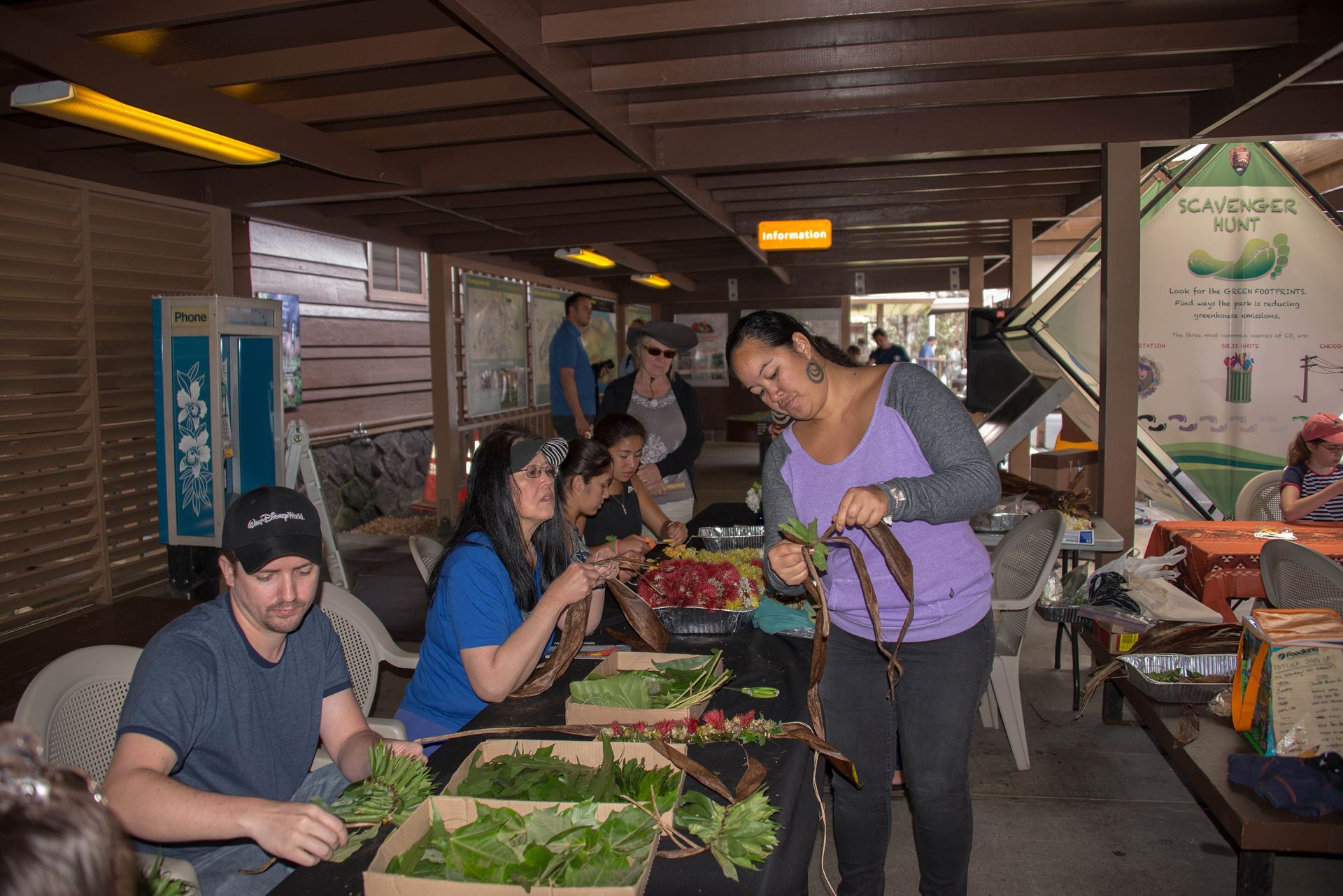 Community members gather around a table to learn lei making